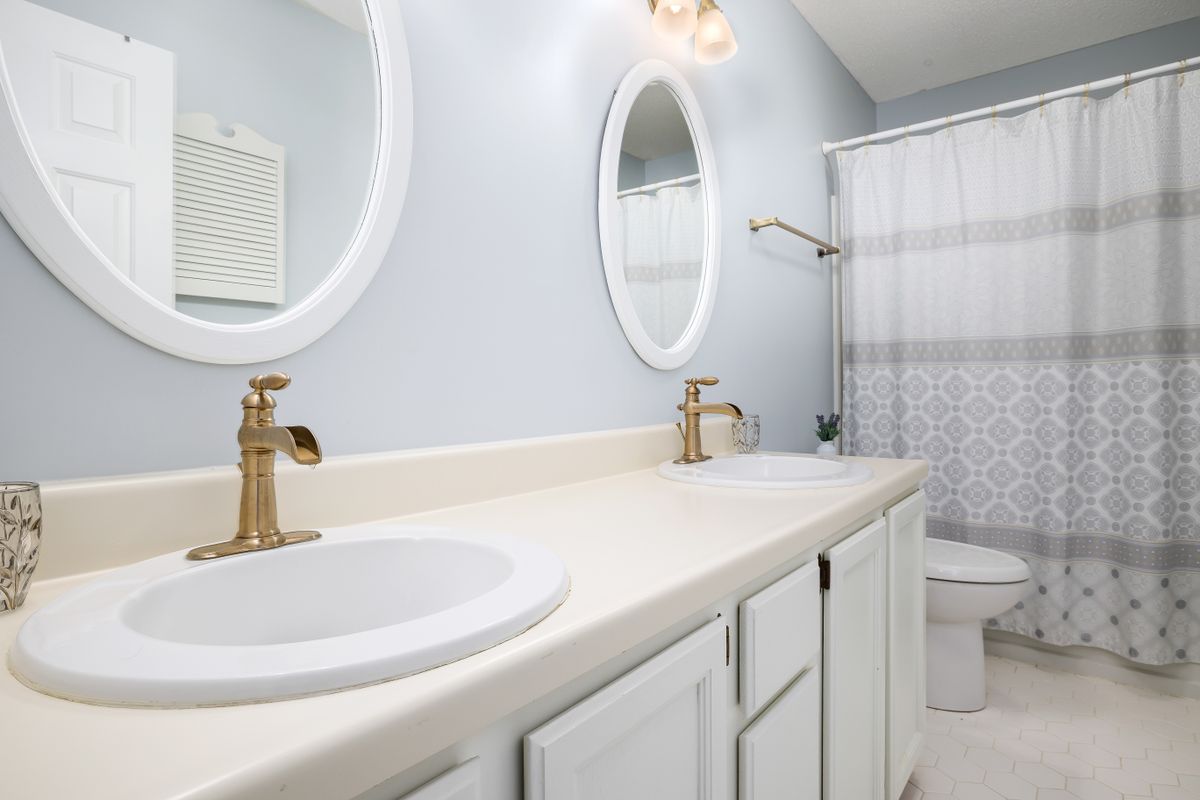 Bathroom vanity with gold faucets and round mirrors illustrating round mirror decor over a vanity Modern bathroom with dual sinks, gold faucets, and round mirrors, illustrating round mirror decor over a vanity