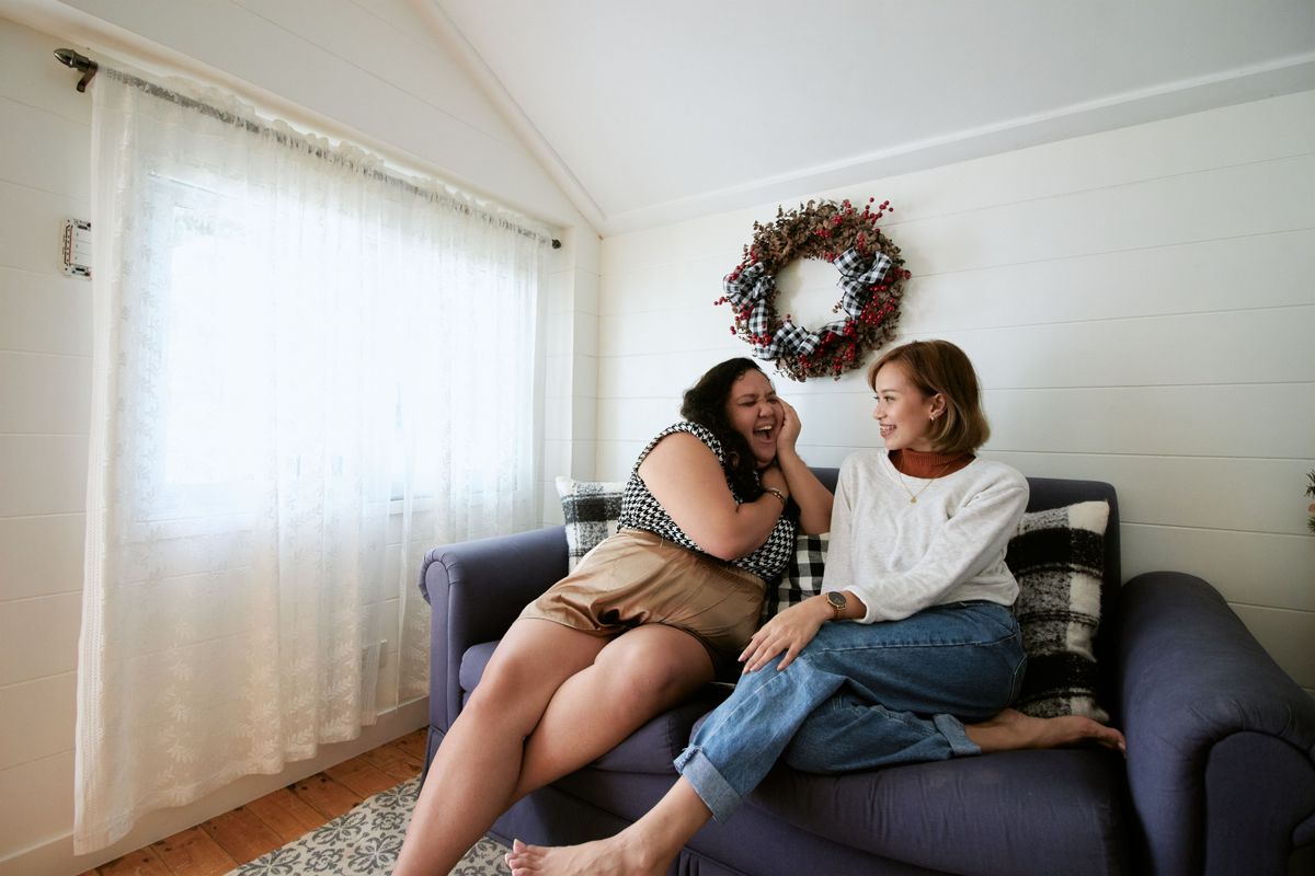 Two people talking on a sofa in a bright, cozy living room, illustrating feng shui conversation seating