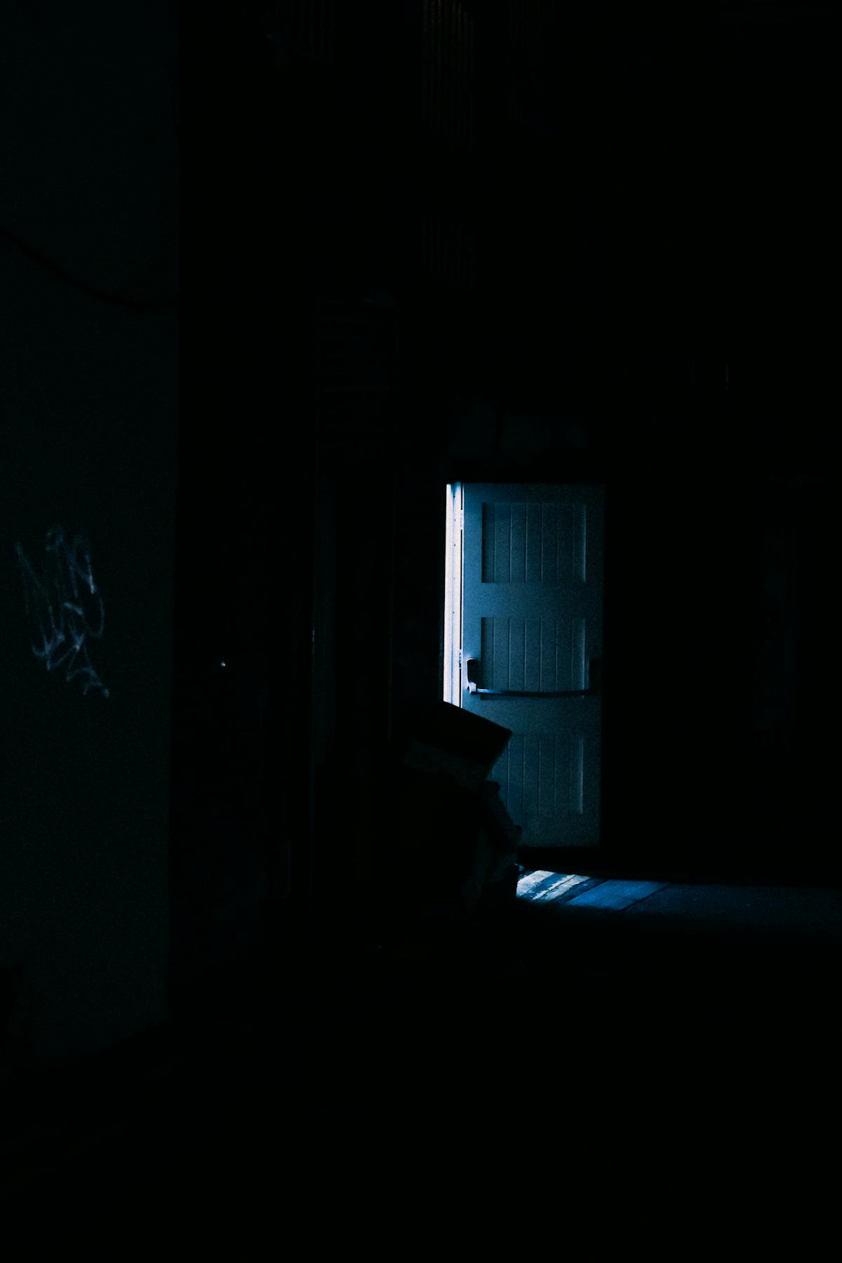 Dark moody doorway suggesting threshold veil and portal symbolism in spiritual language Dimly lit mysterious interior doorway casting long shadows suggesting threshold and spiritual portal symbolism