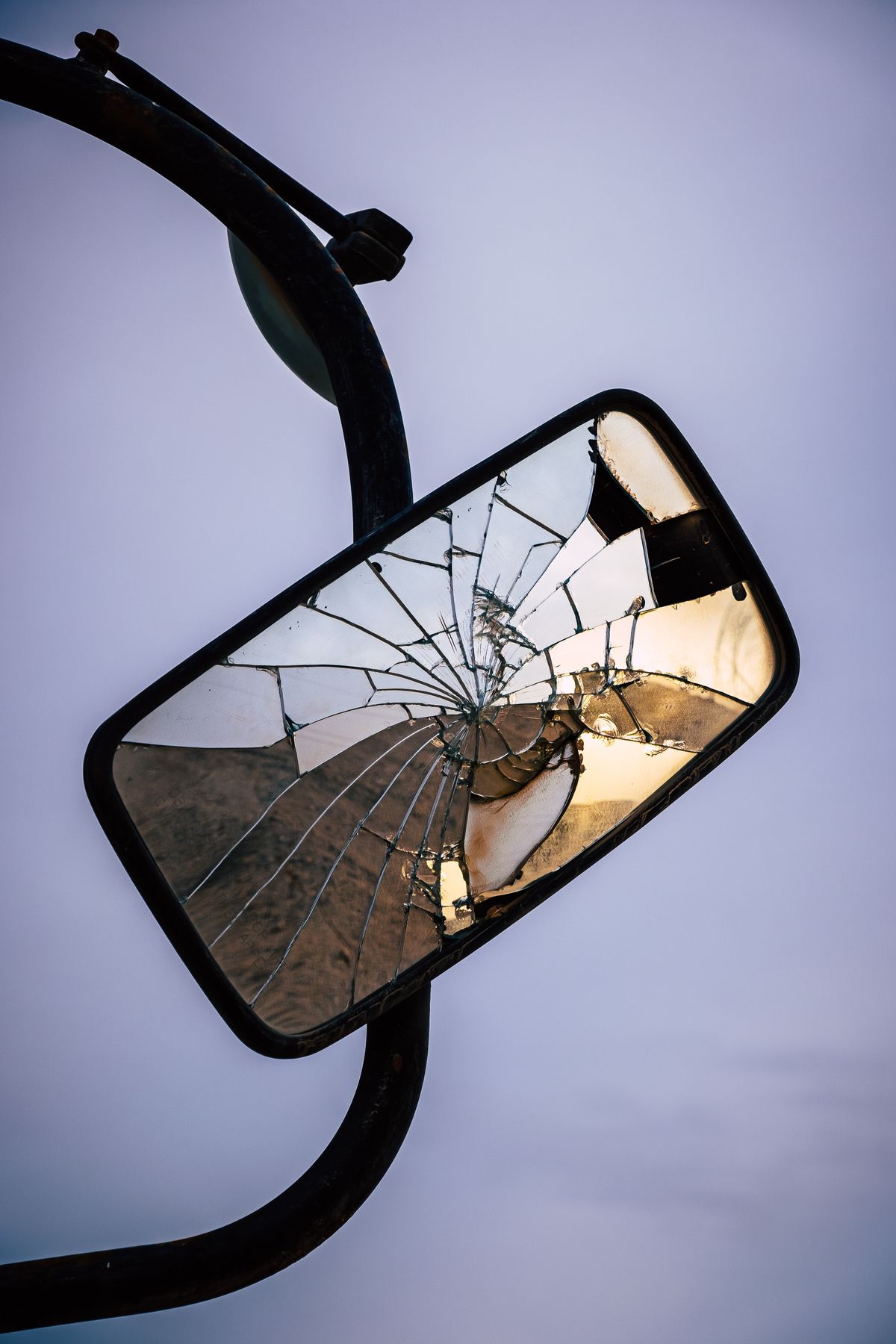 Cracked side mirror with distorted reflection for dream scenario and self-perception symbolism Cracked side mirror close-up reflecting distorted surroundings like fractured self-perception in dreams
