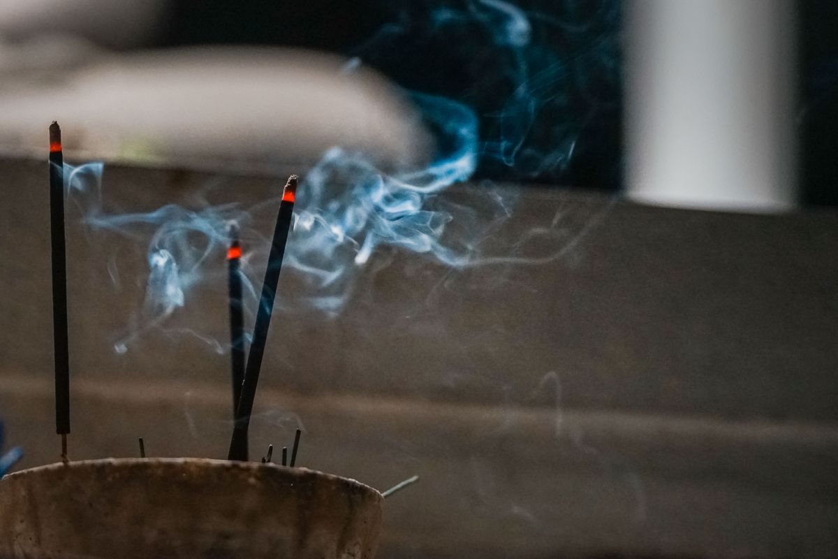 Close-up of burning incense sticks with rising blue smoke representing the cross-cultural cleansing practices linked to the broken mirror spiritual meaning