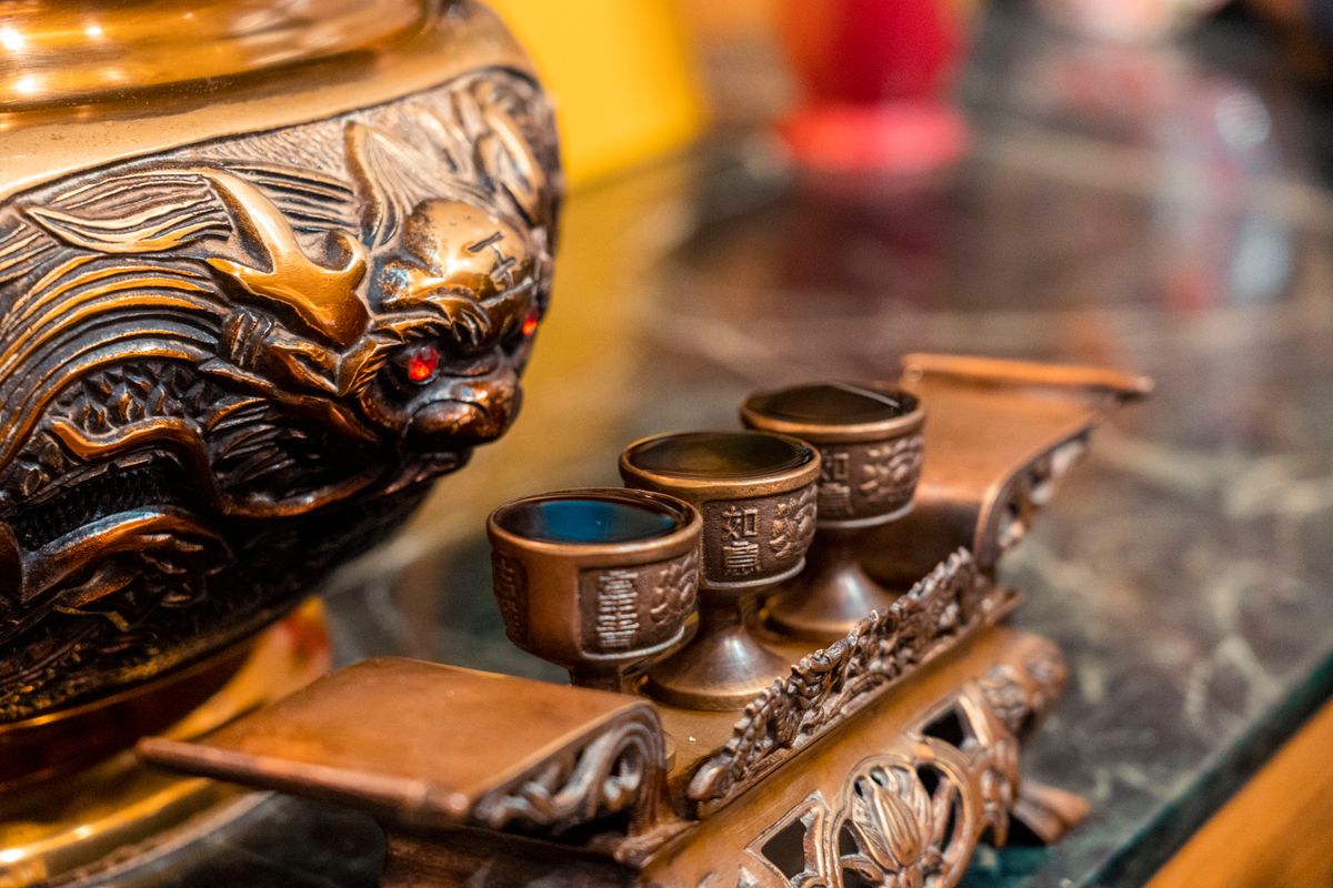 An ornate bronze religious figure alongside decorated chalices on a marble surface representing the sacred use of bronze in ancient worship and the connection between material objects and spiritual meaning in Scripture