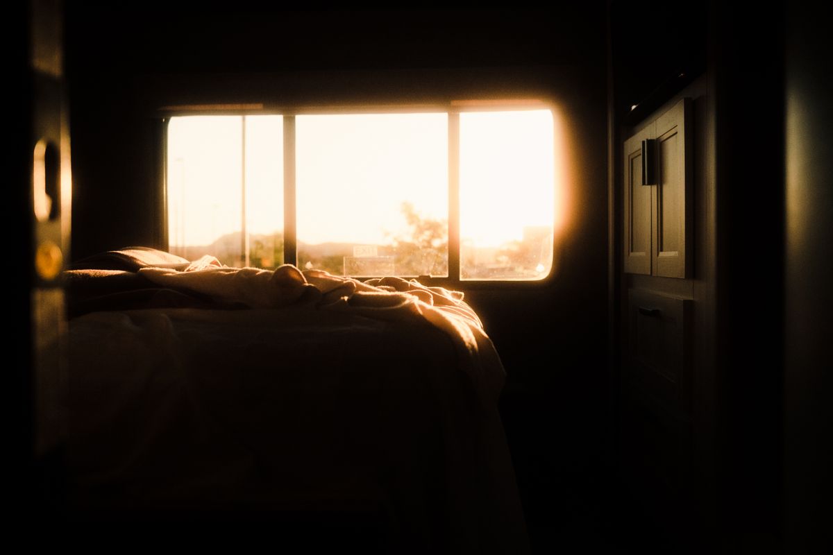 Tranquil bedroom bathed in warm sunrise light through the window, illustrating personalised feng shui sleeping direction