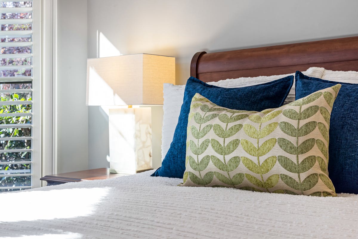Inviting bedroom with decorative pillows and warm sunlight, illustrating how to add feng shui color through accents