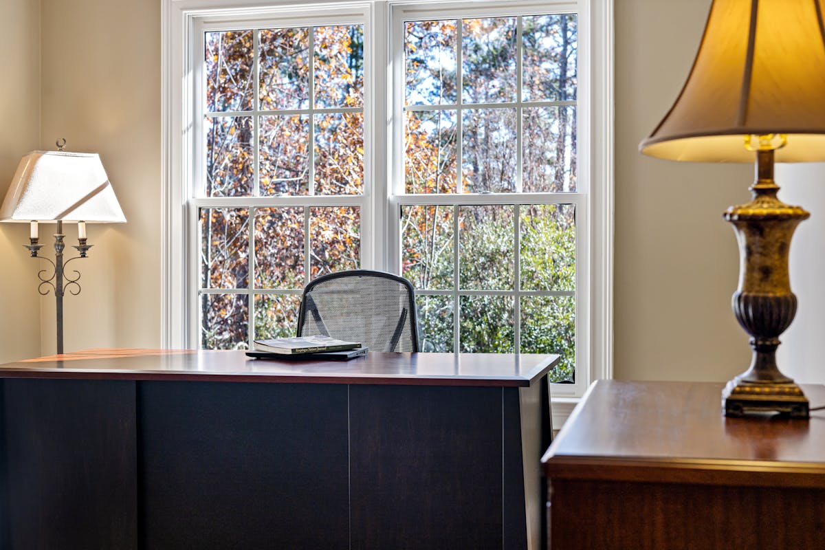Sunlit home office illustrating natural light in a feng shui office layout Cozy home office with a desk and lamp beside a sunlit window, illustrating feng shui office lighting