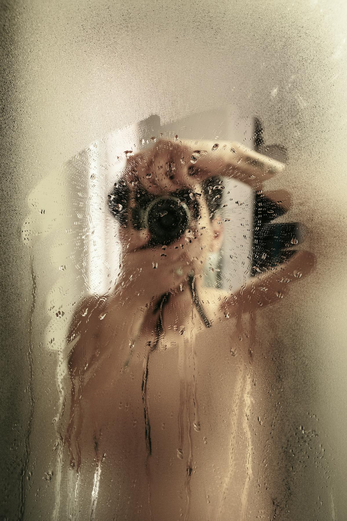 Steamy bathroom mirror with a hand and camera obscuring reflection Artistic steamy bathroom mirror photograph suggesting obscured truth and recurring dreams seeking clarity