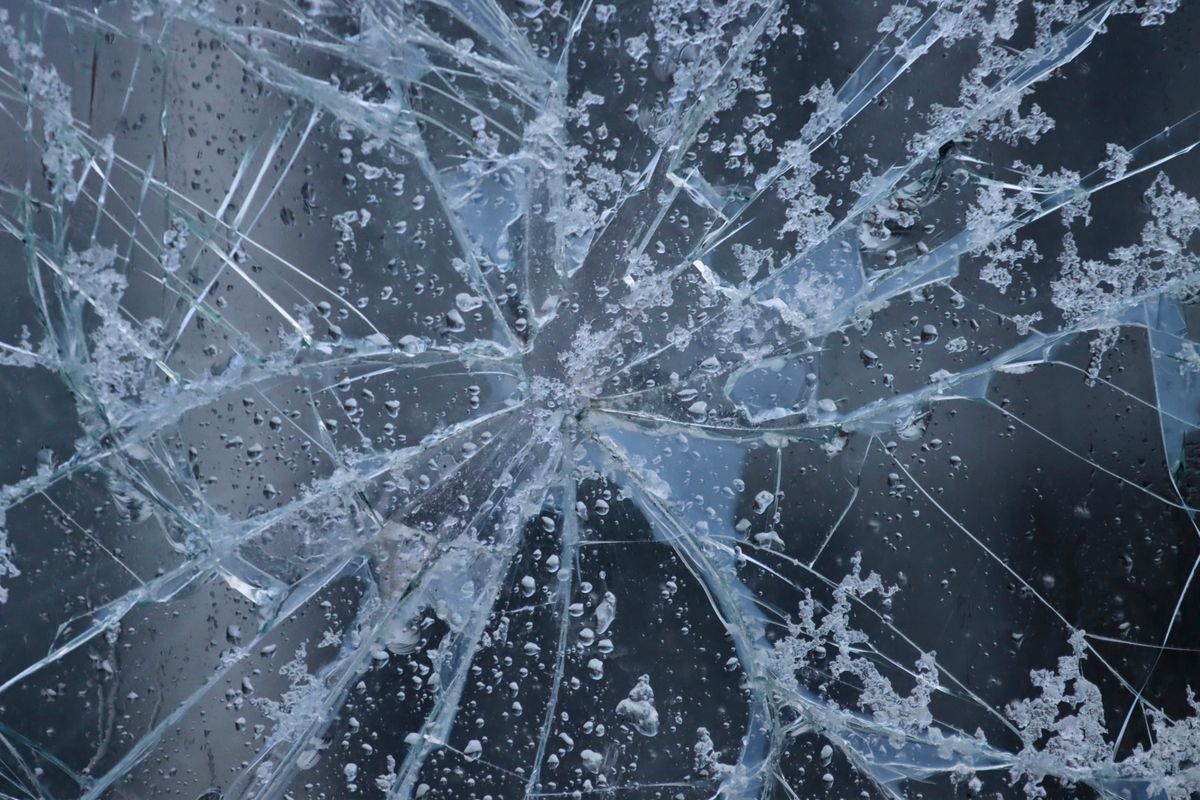 Close-up of frosted shattered glass with water droplets suggesting fragile sharp edges needing careful handling
