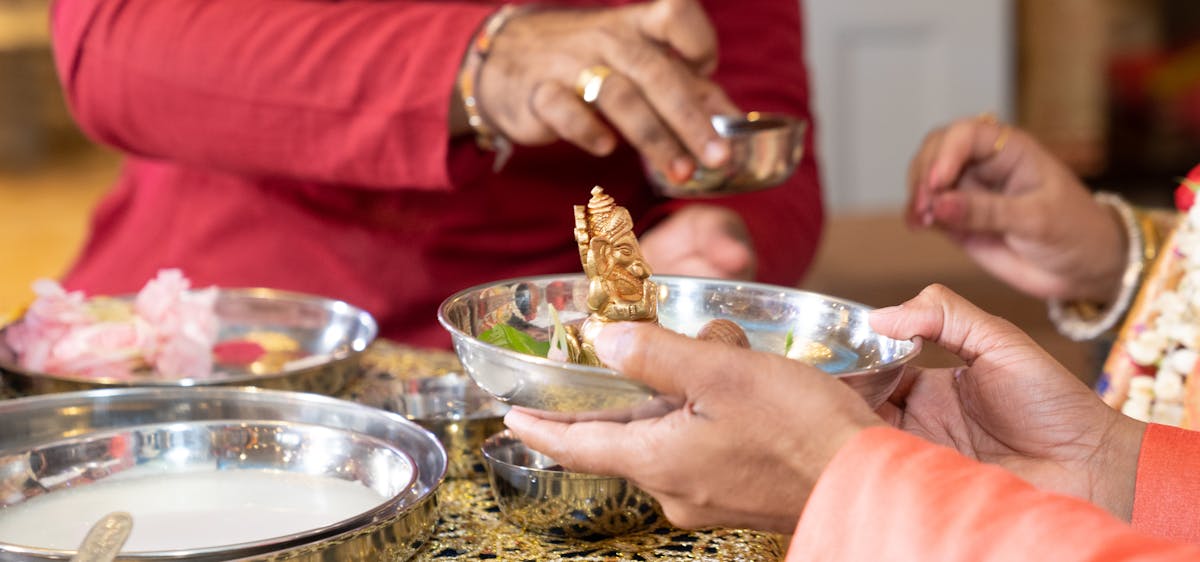 Close-up of a Hindu puja ritual with Ganapati statue and traditional offerings symbolizing Darpana Samarpanam