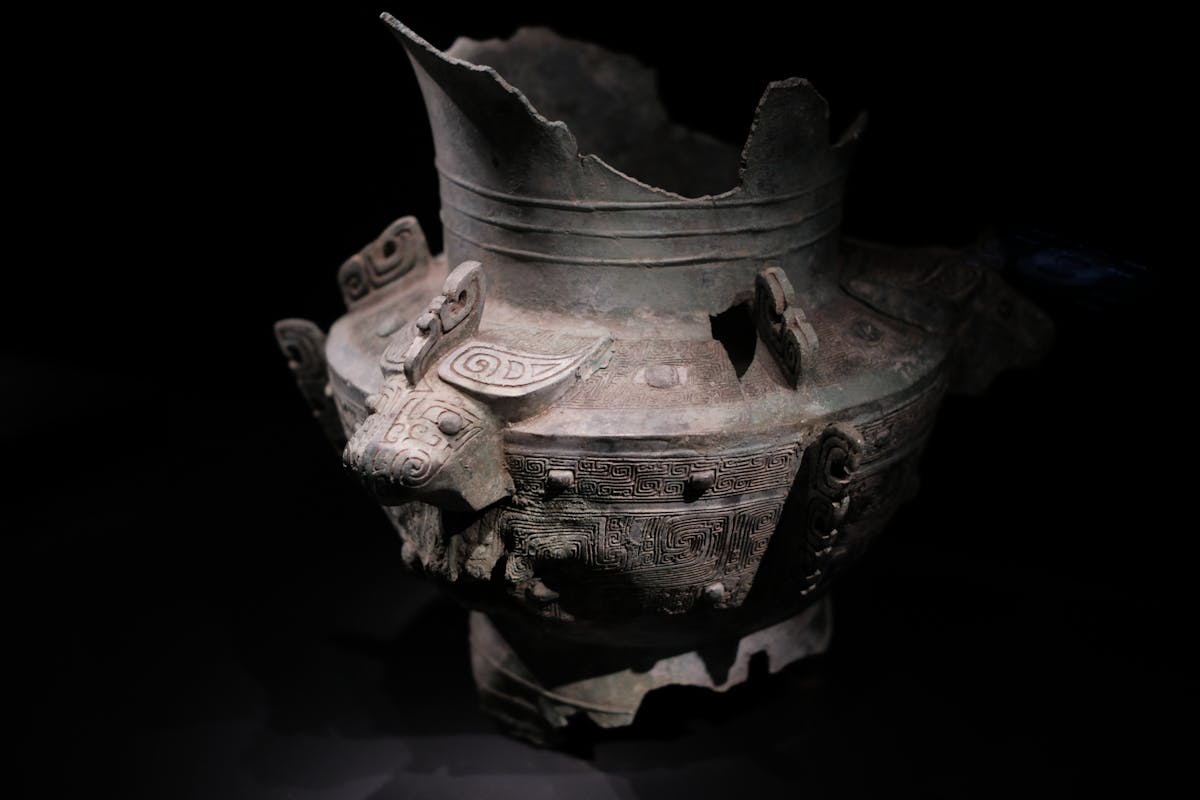 Beautifully detailed ancient Chinese bronze vessel with decorative patterns on display representing the ancient world of bronze mirrors and the history of reflection in sacred contexts