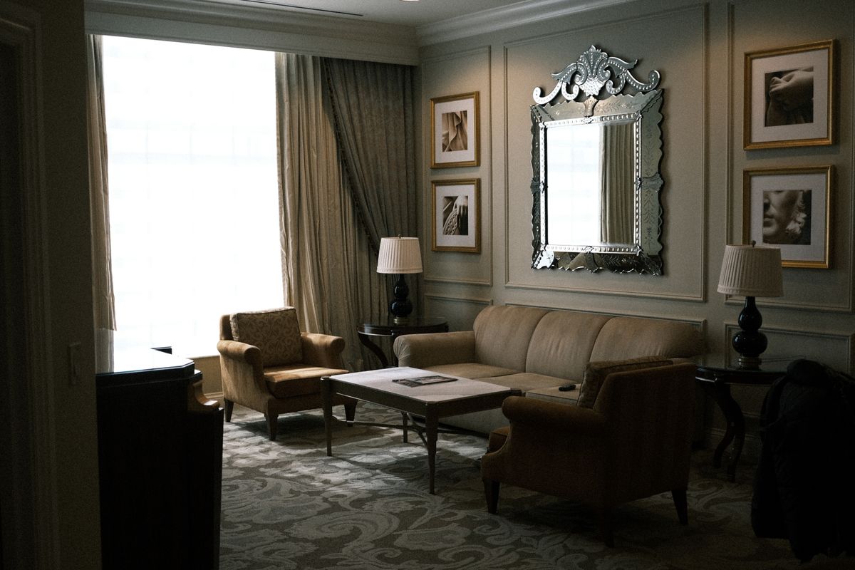 Living room with an ornate mirror illustrating mirror shape and frame styling over a sofa Cozy vintage living room with an elegant ornate mirror and classic furniture, illustrating mirror frame styling