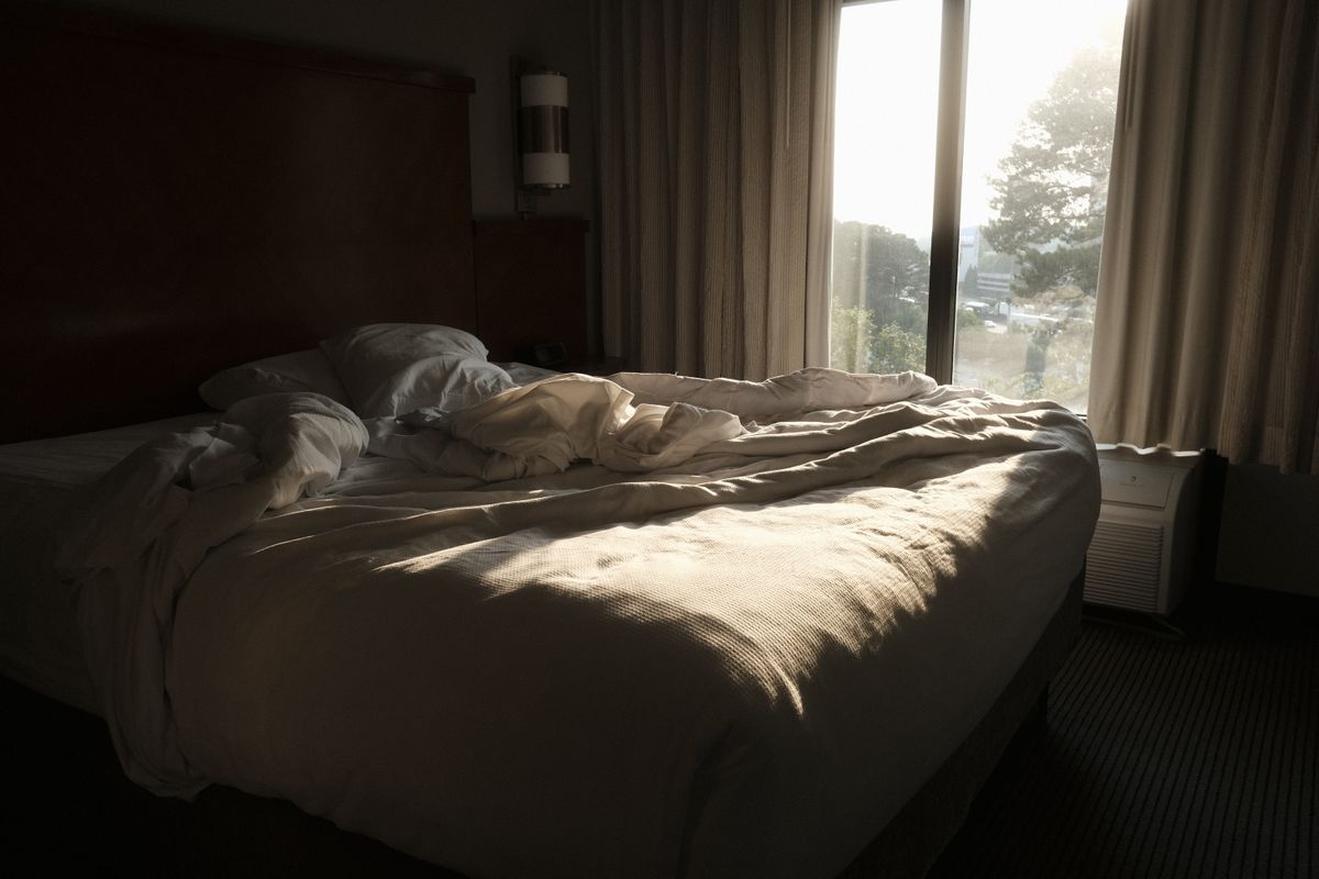 Comfortable bed in soft morning light, illustrating balancing feng shui sleeping direction with bed placement