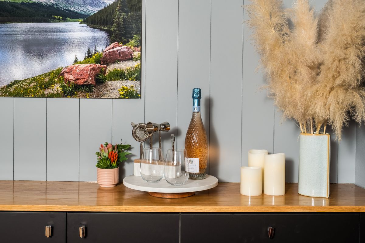 Styled dining sideboard illustrating the correct hanging height for a large mirror over a buffet Styled sideboard with art and candles showing how high to hang a large mirror over a dining buffet
