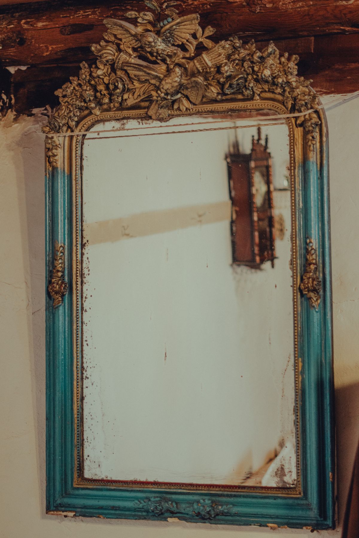 Decorative antique mirror with intricate carved frame leaning against wall in soft indoor lighting
