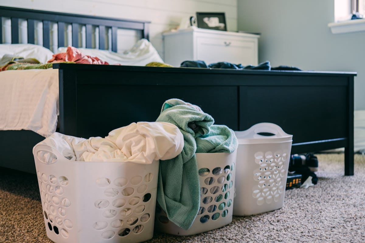 Cluttered bedroom with laundry baskets full of clothing on the floor, illustrating bad feng shui from clutter