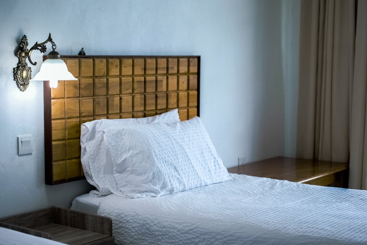 Solid wooden headboard against a wall illustrating feng shui bed support rules Bedroom with a solid wooden headboard against the wall and a wall lamp, illustrating feng shui headboard rules