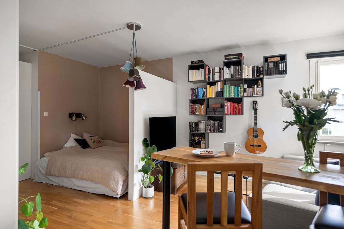 Studio bed in a defined corner illustrating the commanding position in a small space Studio apartment with a cozy bed and bookshelf in a defined sleeping corner, illustrating feng shui bed placement