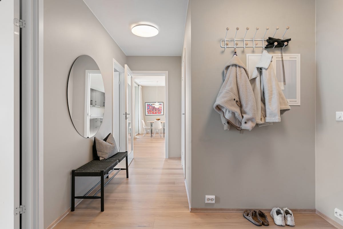 Contemporary hallway with coats and shoes by the door, showing the storage an entryway mirror with hooks replaces