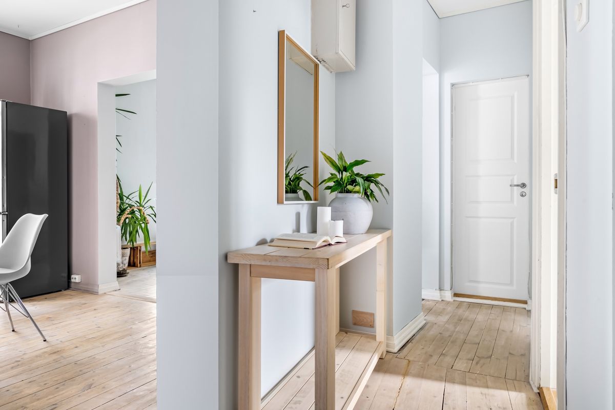 Bright entryway with a mirror reflecting light, illustrating the function of an entryway mirror Bright entryway with a wall mirror and plant reflecting light, showing why an entryway needs a mirror