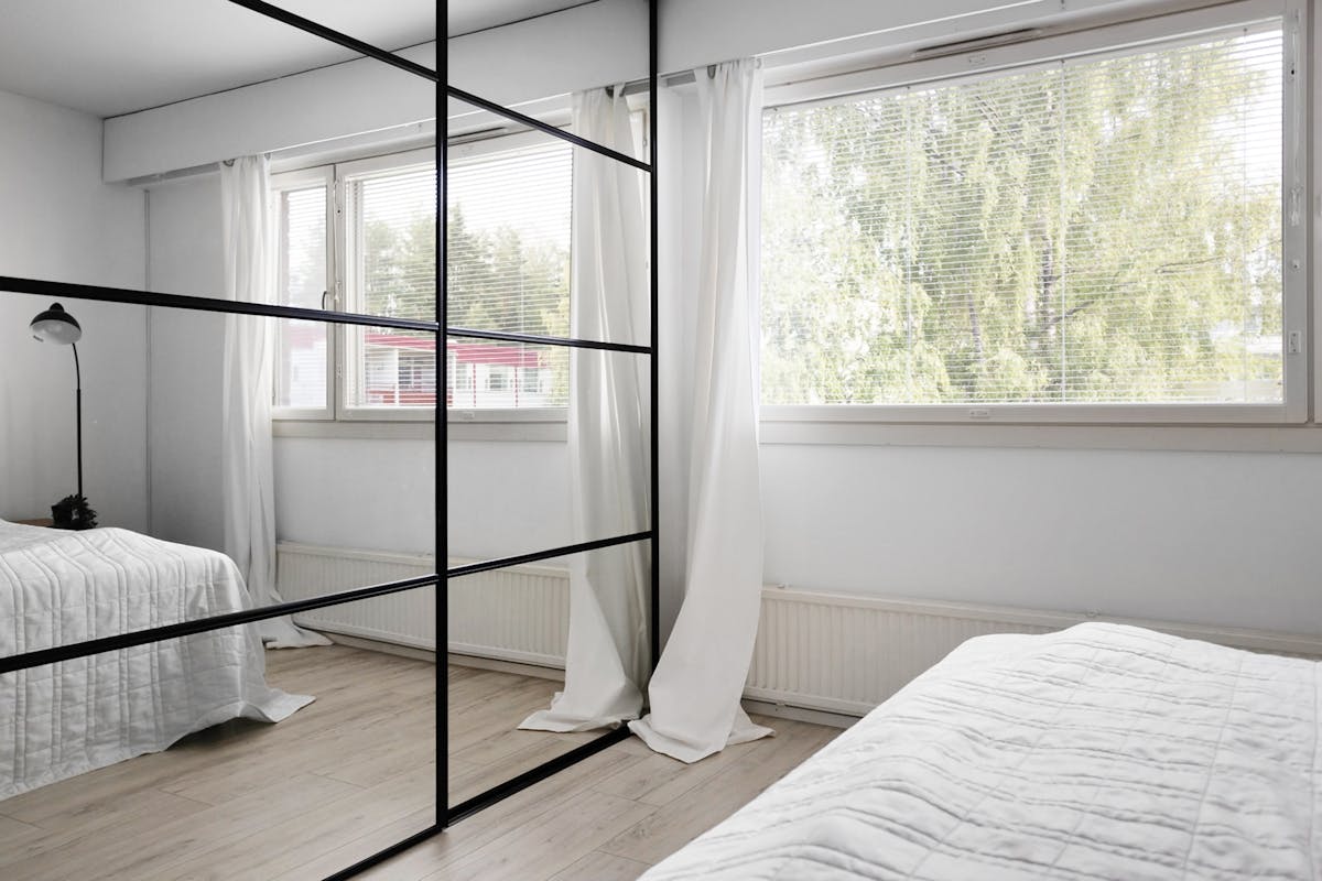 Modern bedroom with securely mounted wall mirrors above the bed Modern minimalist bedroom with large wall mirrors demonstrating secure mirror mounting above the bed