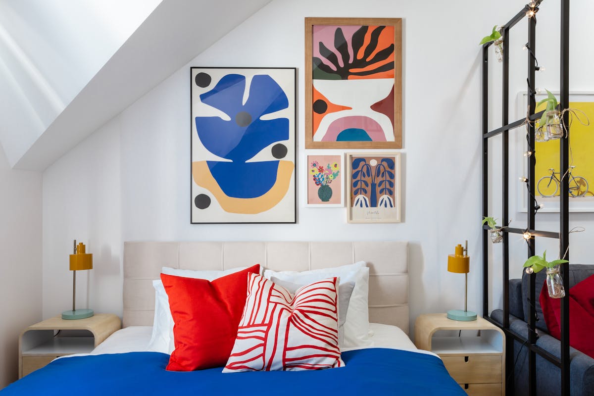 Bedroom gallery wall illustrating a framed-art arrangement for bedroom wall decor Bedroom with a colorful arrangement of framed art on the wall, illustrating a bedroom gallery wall