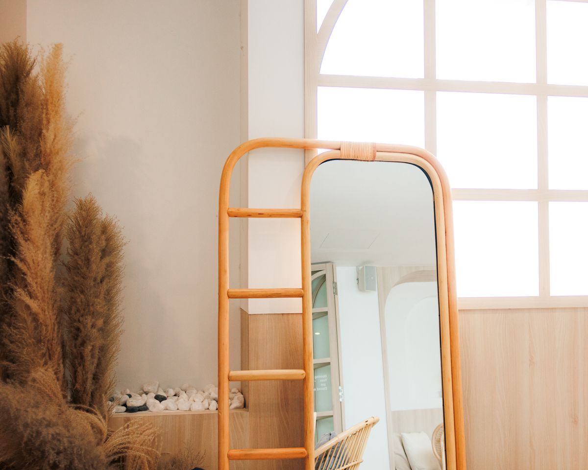 Natural wood framed full length mirror in sunlight illustrating a wooden full length mirror Minimalist interior with a natural wood framed full length mirror and sunlight, illustrating wooden full length mirrors