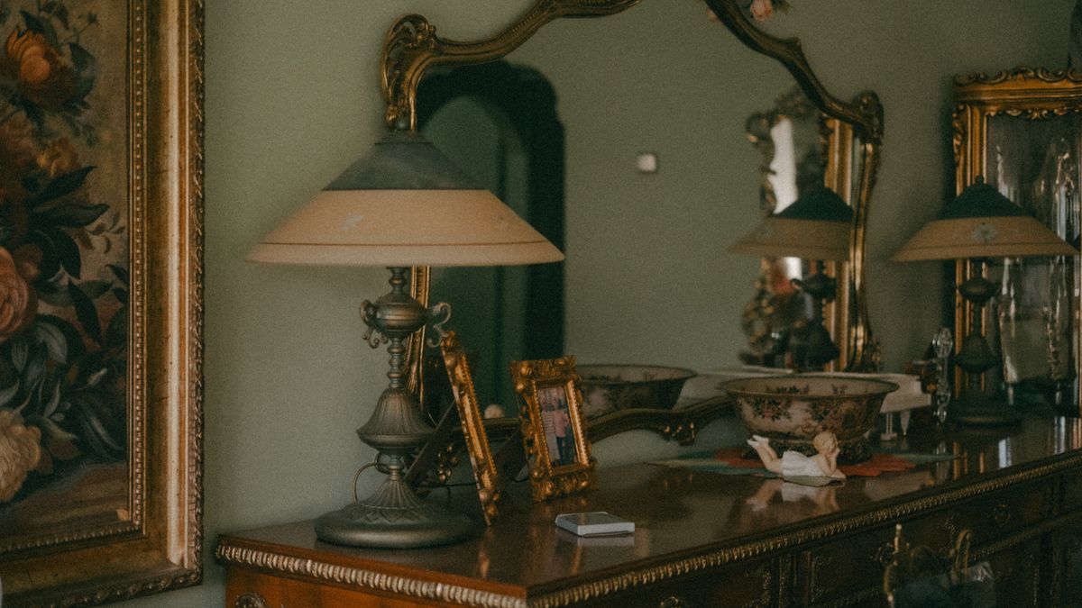 Vintage interior design featuring ornate mirrors, an antique lamp, and a wooden cabinet, representing the serious spiritual practices that still surround mirror use in modern traditions
