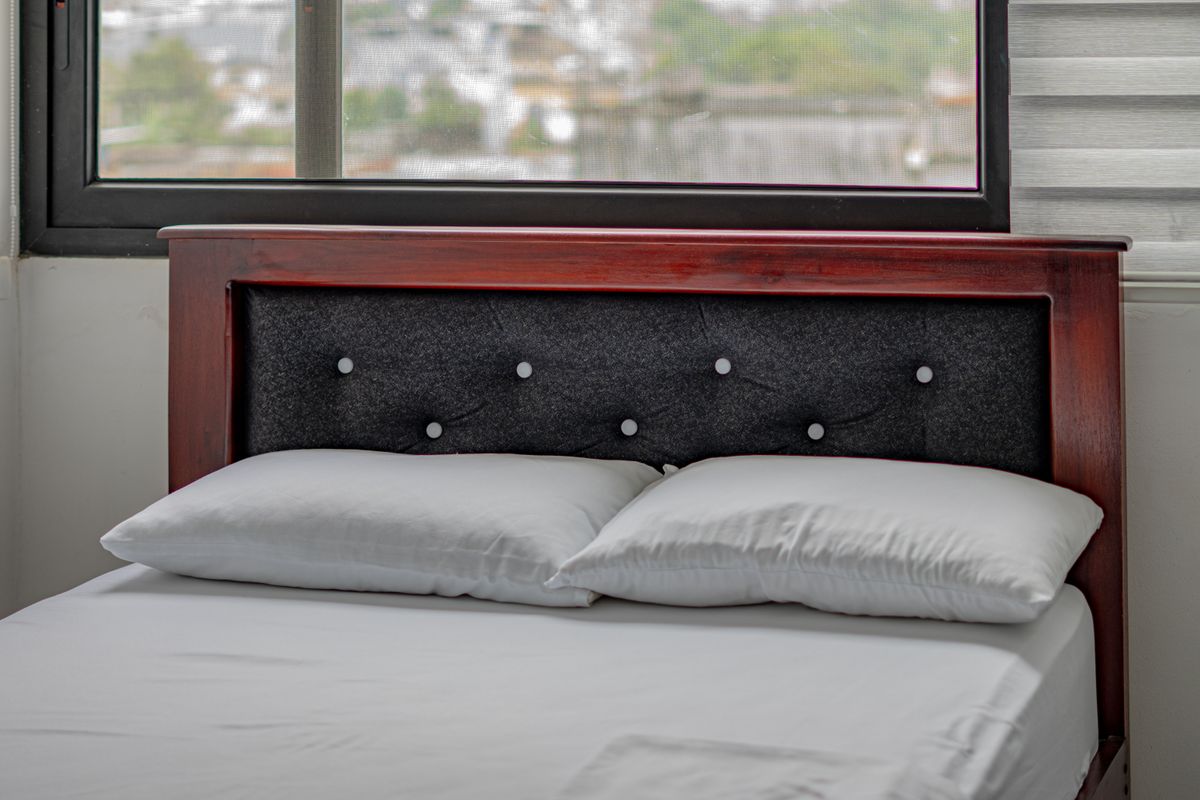 Modern bedroom with a wooden headboard and bed against a solid wall, illustrating the feng shui commanding position
