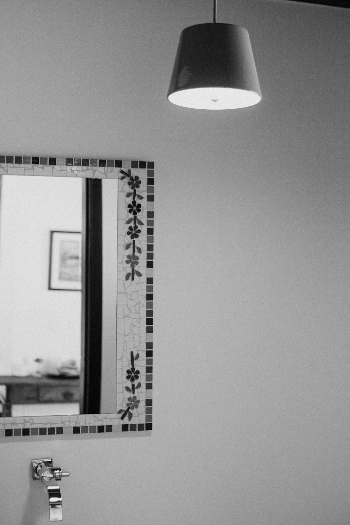 Minimalist bathroom mirror near natural light evoking the feng shui mirror facing window placement question Minimalist black and white bathroom with decorative tiled mirror and natural light fixture illustrating the feng shui mirror facing window question and light redirection