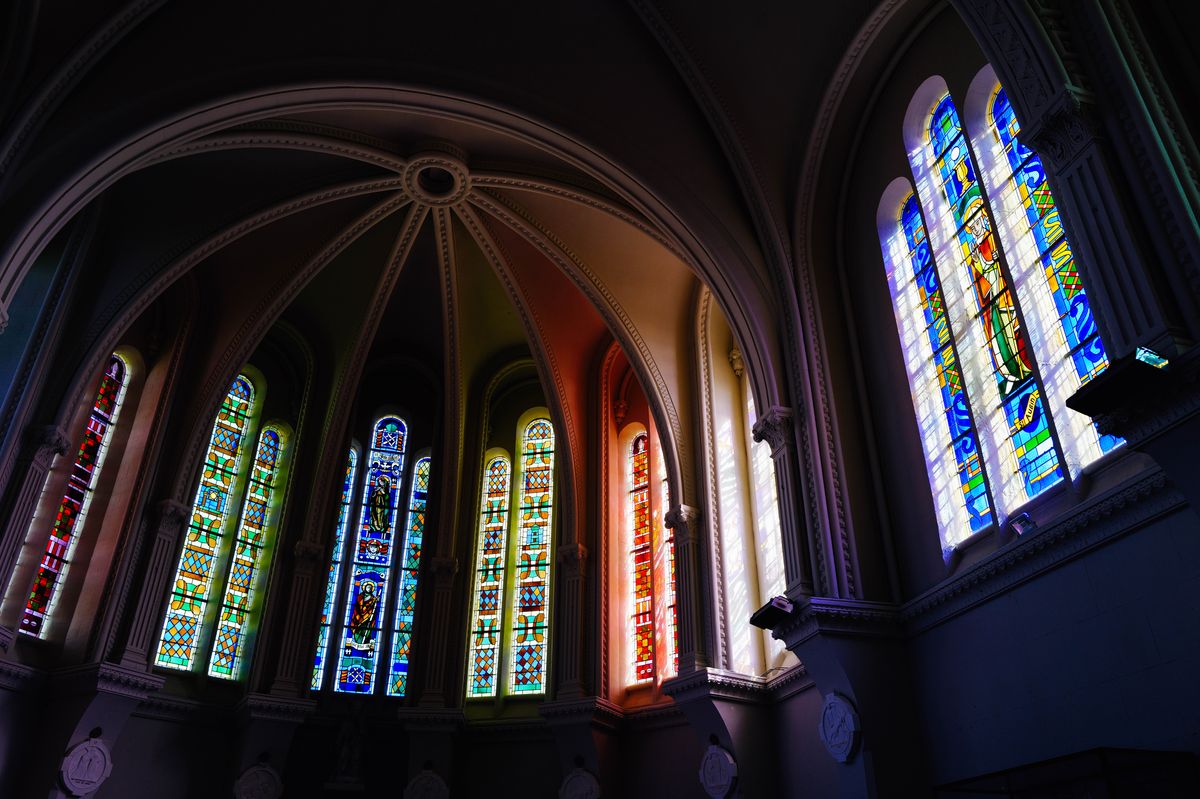 Vibrant stained glass windows in a gothic cathedral interior capturing colorful light representing the spiritual clarity that Scripture promises against the dim glass darkly of present understanding