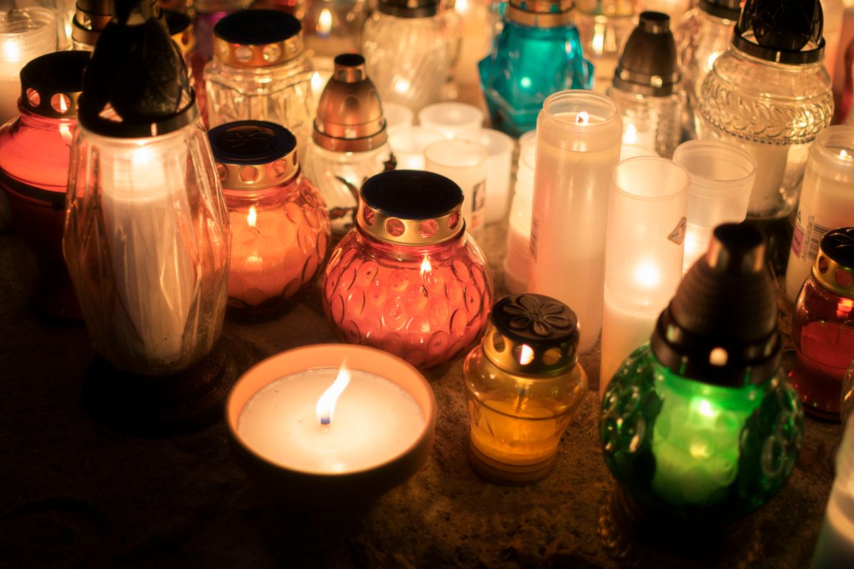 Colorful votive candles creating a warm spiritual ambiance at an outdoor memorial representing the connection between covering mirrors in mourning and the biblical call to redirect attention from vanity to eternity during grief