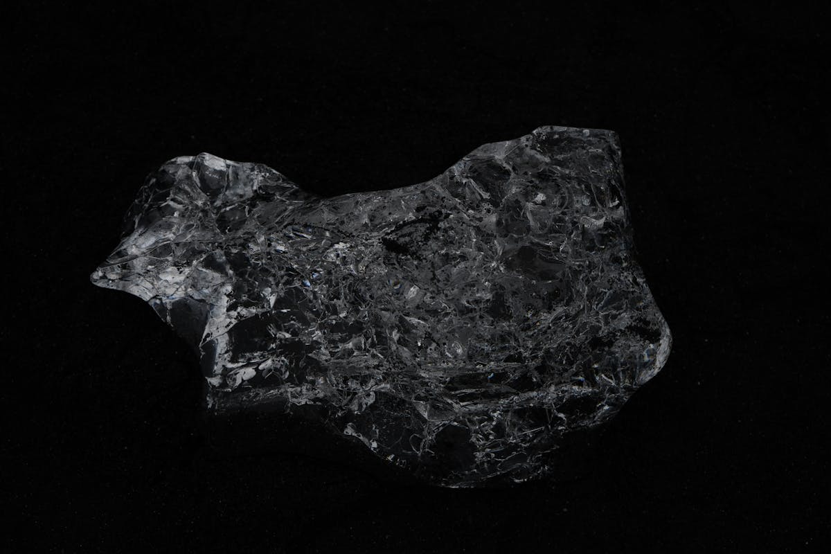 Dark glimmering black obsidian stone against a black background representing the void symbolism behind black mirror scrying