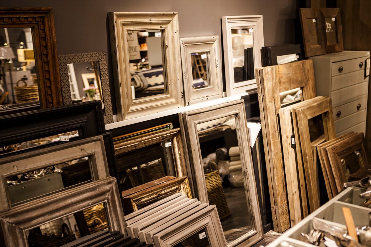 Assorted wood mirror frames in different shapes illustrating round, oval, arched, and wavy wood mirrors Display of vintage-style wood mirror frames in various shapes in a cozy interior, illustrating wood mirror frame shapes