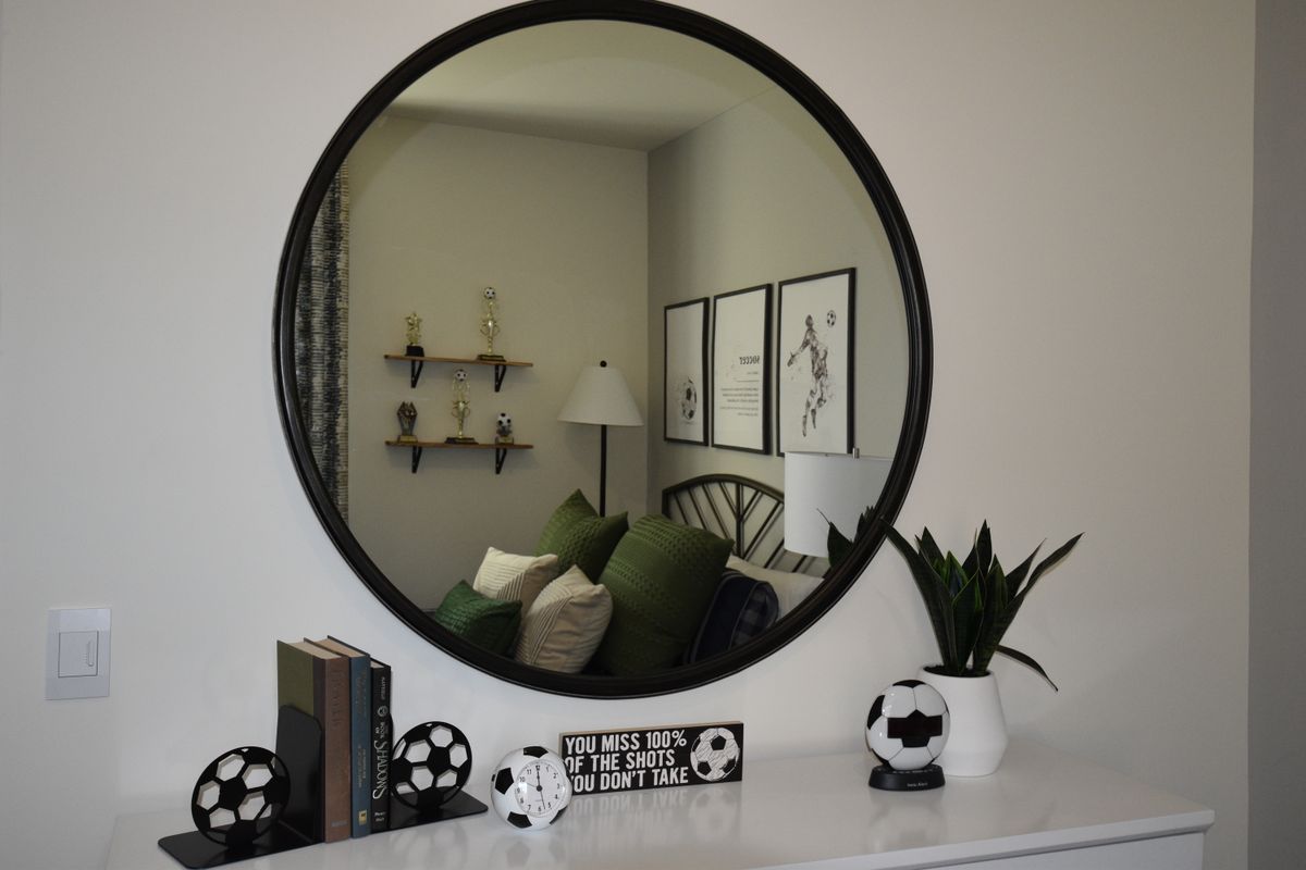 Round mirror mounted on a bedroom wall reflecting the room, showing shape options for a mirror over a nightstand