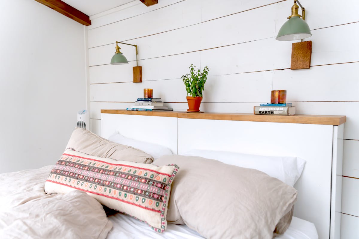 Bedroom with plants and soft wall lighting illustrating lighting as bedroom wall decor Minimalist bedroom with hanging plants and soft lighting, illustrating wall lighting and greenery in bedroom decor