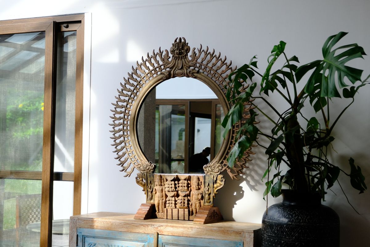 Decorative Indian mirror with houseplant in Nandi Hills suggesting Vastu-friendly placement and domestic mirror symbolism Ornate decorative mirror with intricate design and indoor greenery in a Nandi Hills setting suggesting Vastu-aligned placement in an Indian home