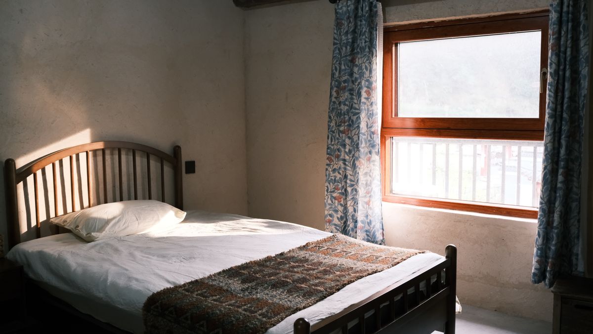 Bed near a window illustrating feng shui bed positions to avoid Bedroom with a bed beside a sunlit window, illustrating feng shui bed positions to avoid such as under a window