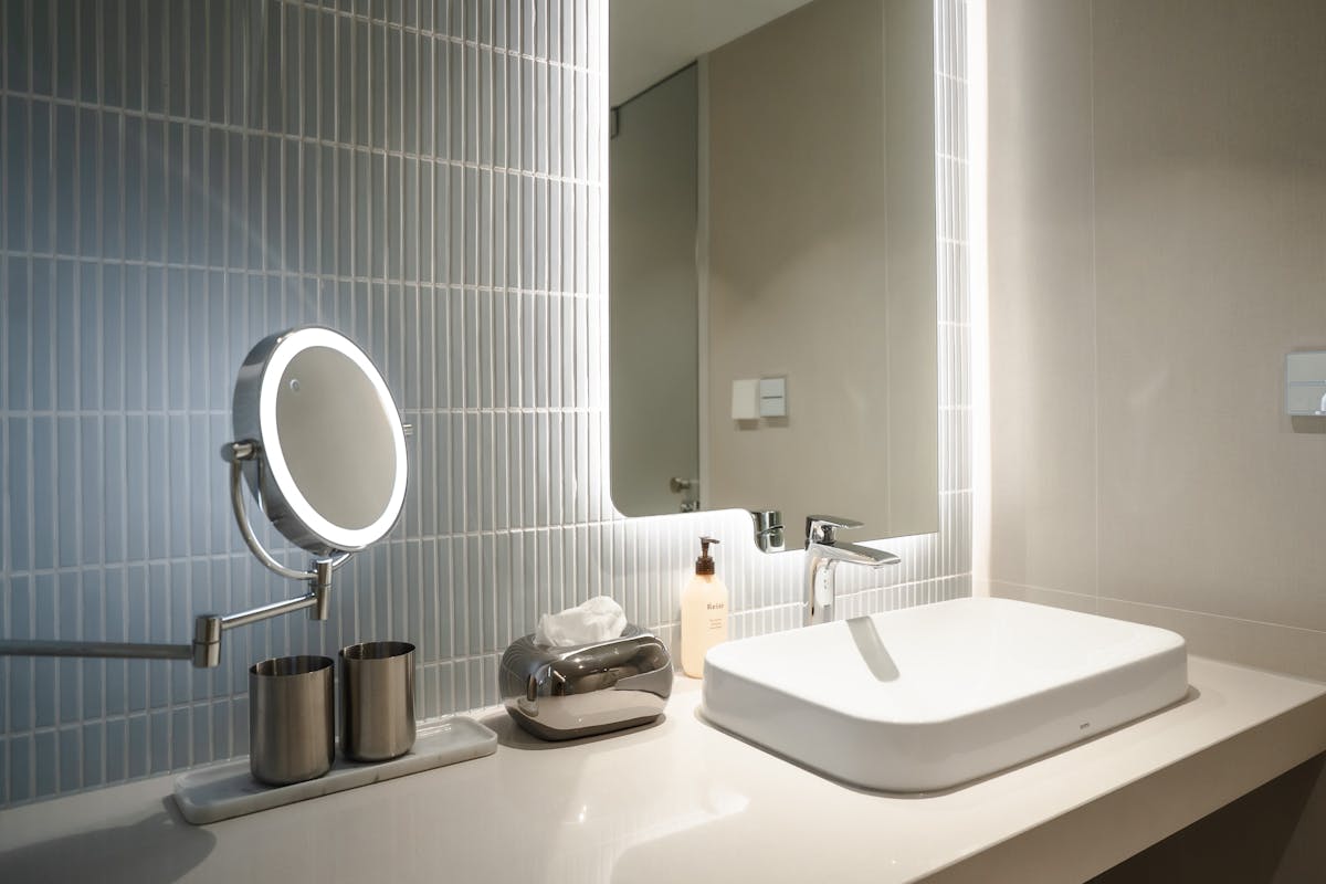 Minimalist white bathroom vanity with round mirror and warm side lighting