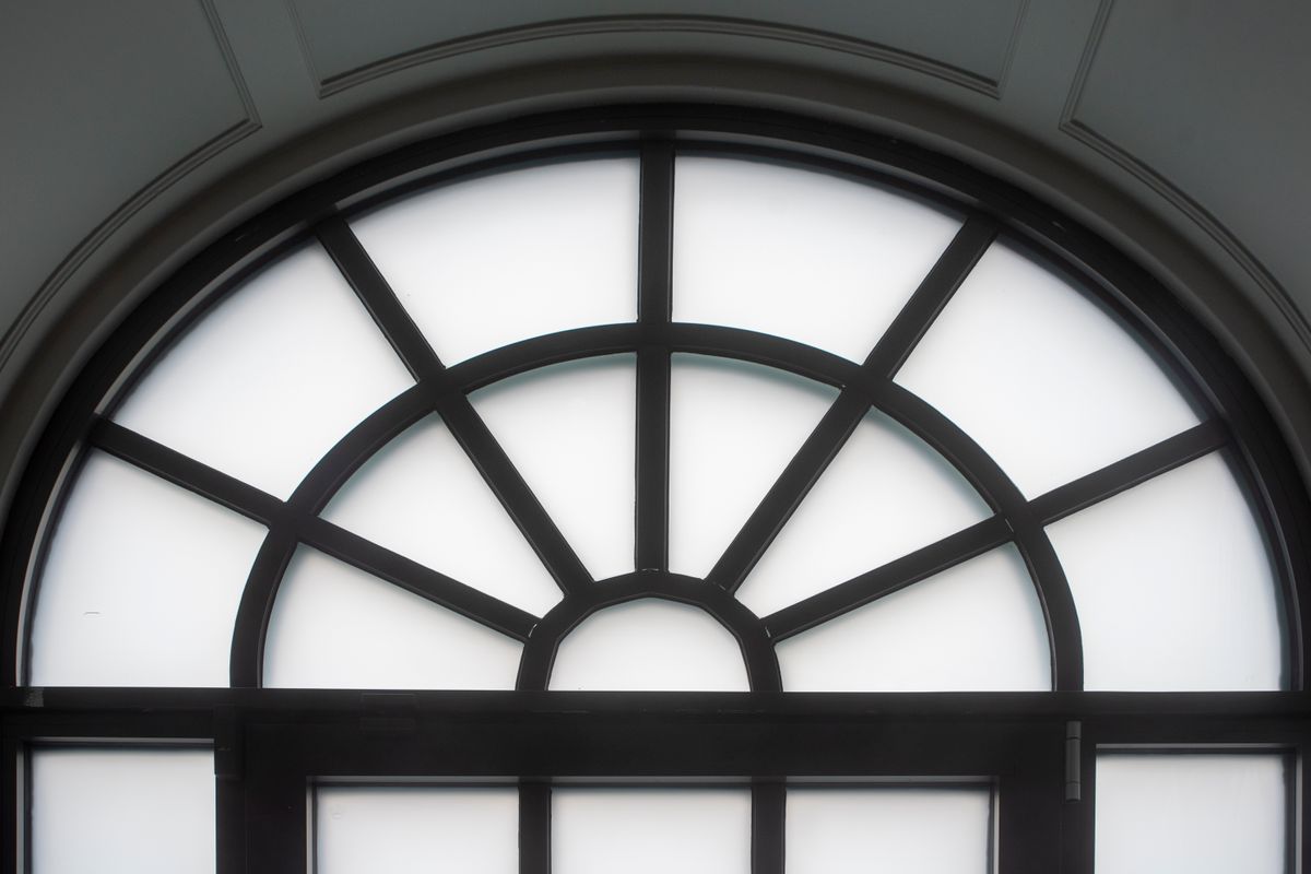 Black-framed arched window illustrating the window-pane arched mirror look Elegant arched window with a classic black frame and frosted glass, illustrating a window-pane arched mirror