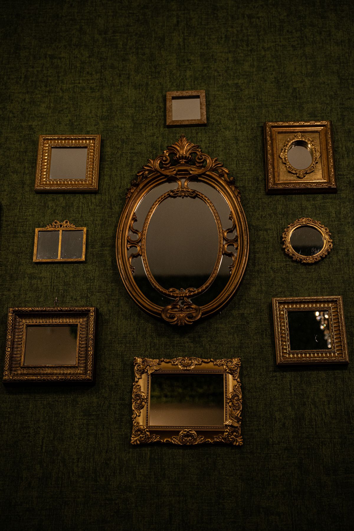 Vintage ornate mirrors on wall illustrating cultural mirror symbolism and reflection Collection of vintage ornate mirrors on textured green wall showing historical mirror craft and spiritual symbolism