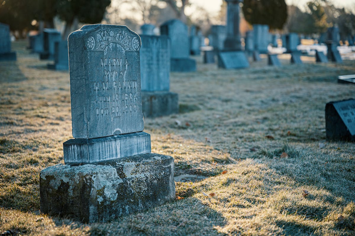 Old stone cemetery with weathered gravestones and moss-covered markers under overcast sky in autumn light