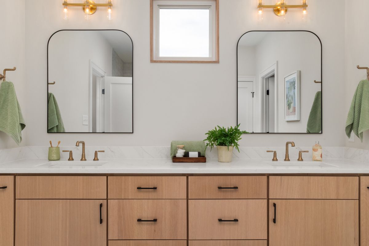 Soft daylight on empty bathroom mirror above washbasin with neutral decor