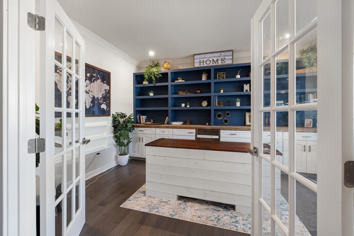 Home office with color and materials illustrating the five elements in a feng shui office layout Stylish home office with blue shelves and a white desk, illustrating feng shui five elements and colors