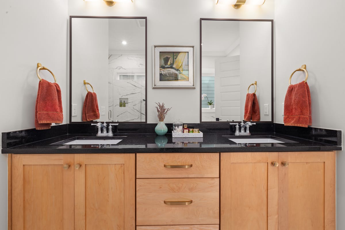 Rectangular black-framed mirrors over a black countertop illustrating black square and long mirror decor Modern vanity with black countertop and rectangular framed mirrors, illustrating black square and long mirrors