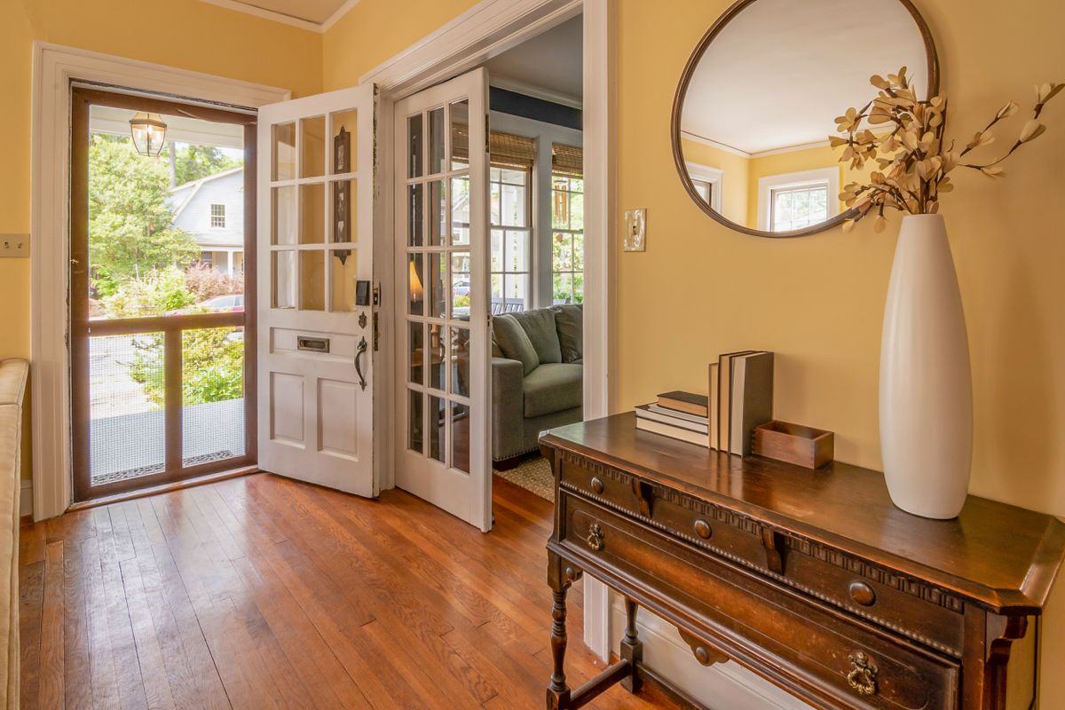 Bright entryway with mirror and natural light evoking feng shui mirror placement at the entrance Sunlit entryway with wooden dresser ornate mirror and decorative branch vase illustrating feng shui mirror entryway placement for welcoming Chi