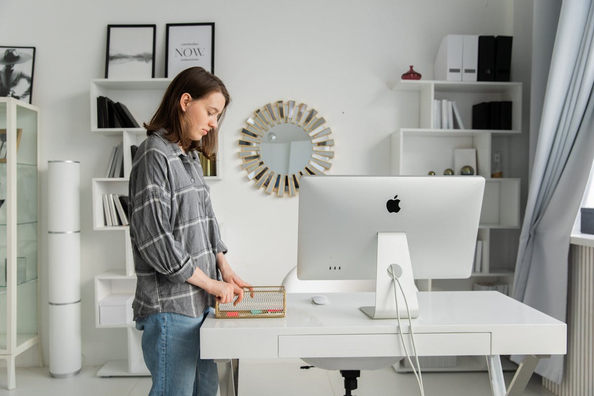 Organizing a home office desk illustrating decluttering and support in a feng shui home office Person organizing a tidy home office desk with shelves, illustrating decluttering in a feng shui home office
