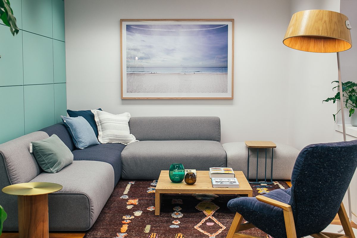 Living room with a grey sofa against a wall facing the room, illustrating the feng shui command position
