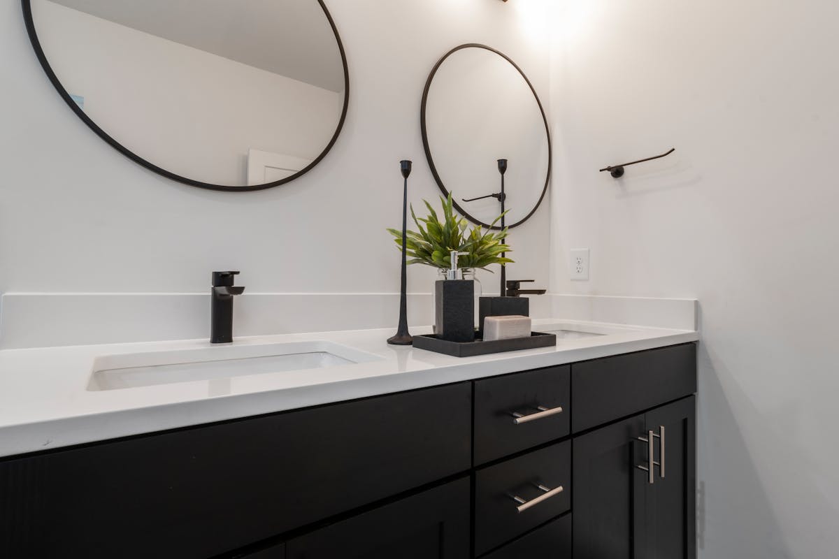 Black and white vanity illustrating why black-framed mirror decor works through contrast Sleek black and white bathroom vanity with framed mirrors, illustrating why black mirror decor works