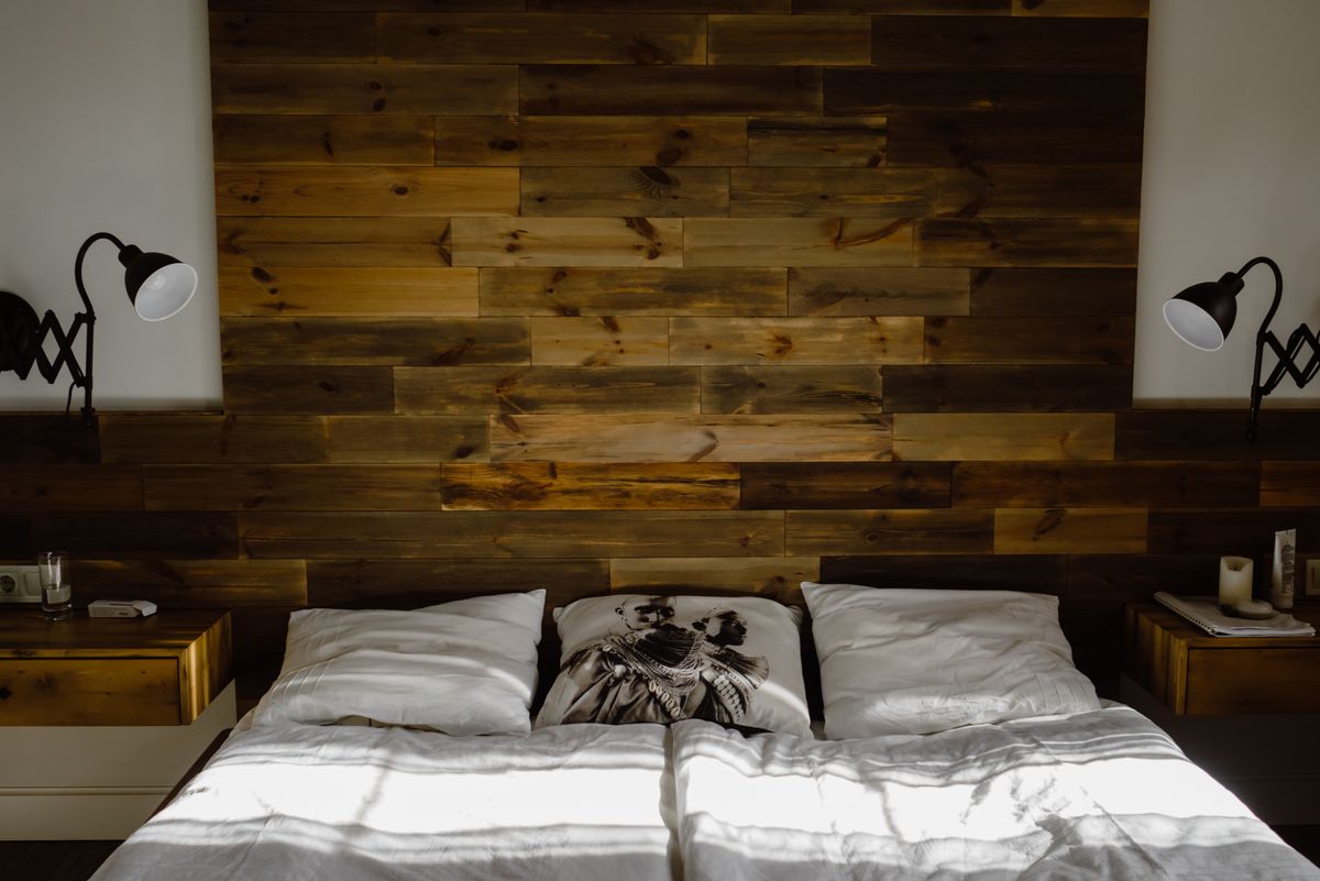 Solid headboard against a wall illustrating the feng shui bed wall placement rule Bedroom with a solid wooden headboard against the wall, illustrating the feng shui rule for which wall the bed goes against