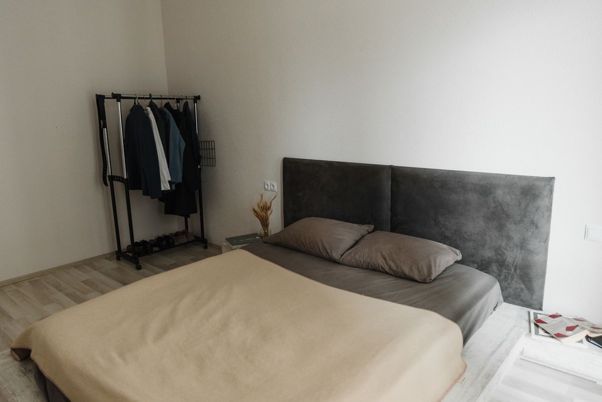 Minimalist bedroom with beige bedding and a soft grey headboard, illustrating grounding feng shui earth tones