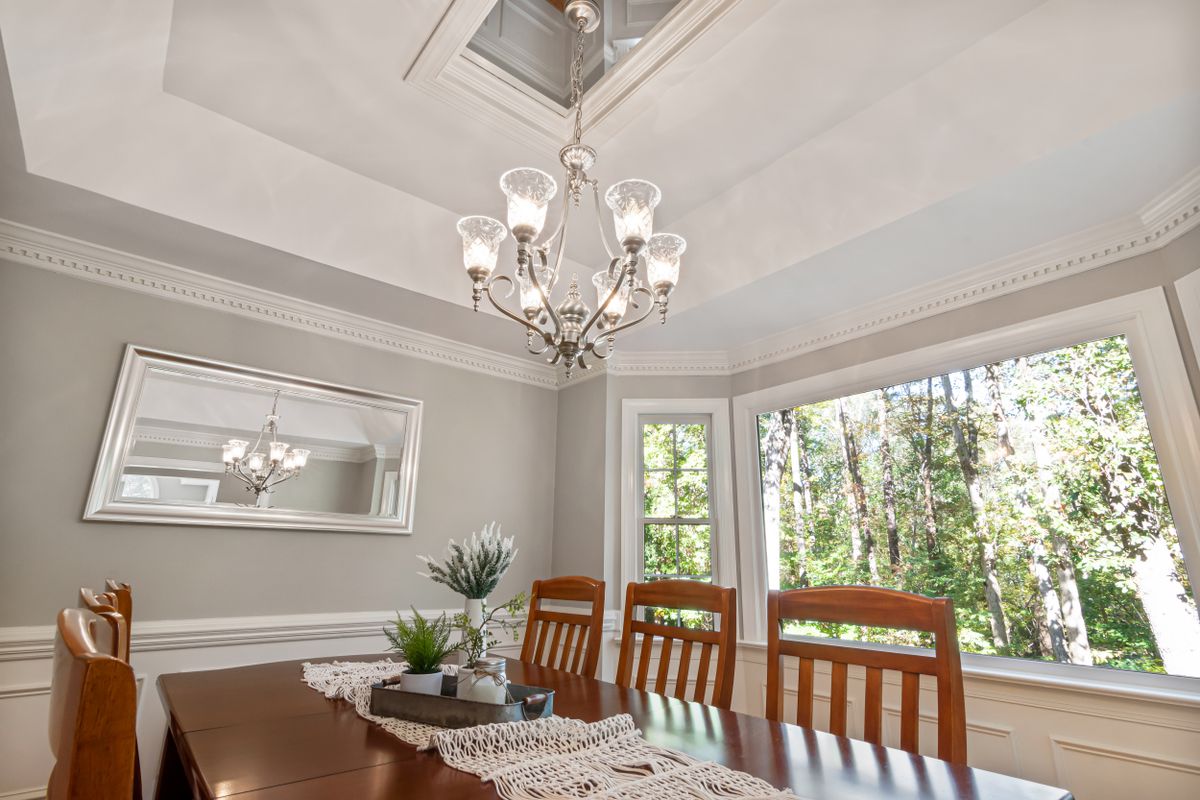 Dining room with a chandelier whose light a mirror can double, a dining room mirror lighting idea Dining room with a chandelier and wooden furniture where a mirror can double the light